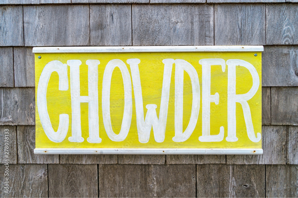 Rustic hand painted seafood sign on a wall of weathered shingles.