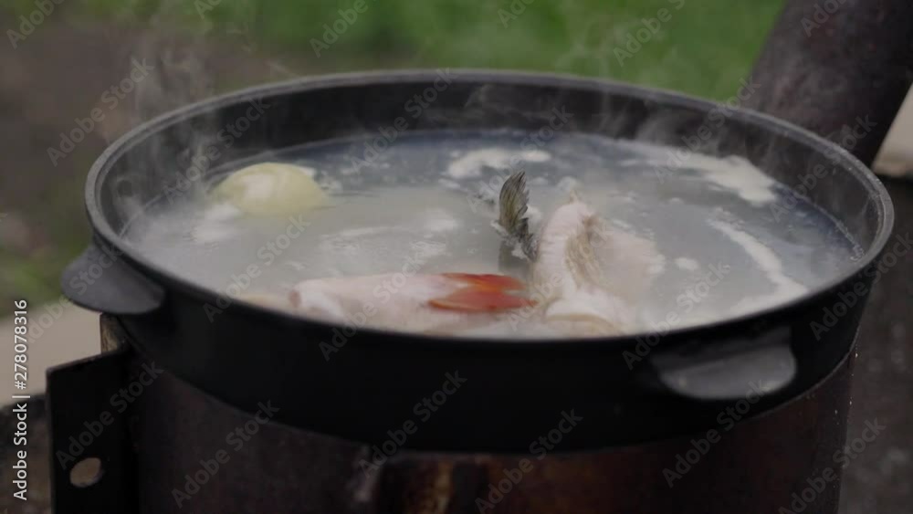 Cooking fish soup outdoors, on the surface of the water foam and plentiful steam, close-up shot, summer Cooking fish soup outdoors, on the surface of the water foam and plentiful steam, close-up shot, summer