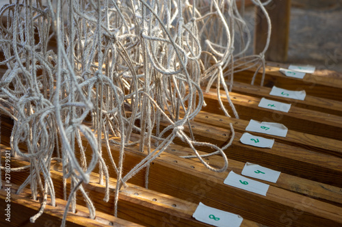 Numbered treadles tied up with cords to a wooden hand weaving loom