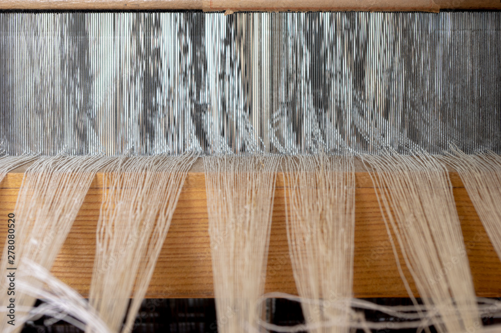 Linen yarn running through the reed of a hand weaving loom