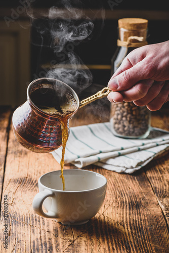 Pouring turkish coffee into white cup