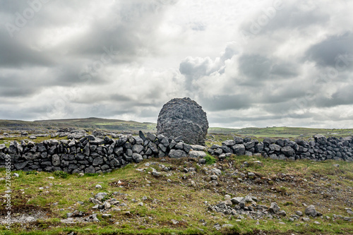 Beautiful view in the Caher Valley of a giant stone next to a stone fence in the Burren, Wild Atlantic Way, wonderful cloudy spring day in county Clare in Ireland photo