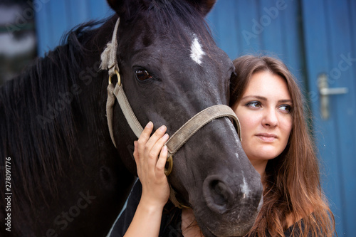 portrait of young woman with her black horse