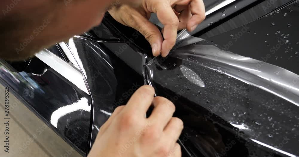 Close up to PPF installation process on a front headlight and hood. PPF is a Paint Protection Film which protect paint from scratches and stone chips. Concept of: Guard, Protect, Car, New, Work. Close up to PPF installation process on a front headlight and hood. PPF is a Paint Protection Film which protect paint from scratches and stone chips. Concept of: Guard, Protect, Car, New, Work.