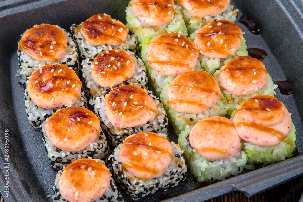Set of baked rolls in a plastic box. Food delivery from sushi restaurant Set of baked rolls in a plastic box. Food delivery from sushi restaurant