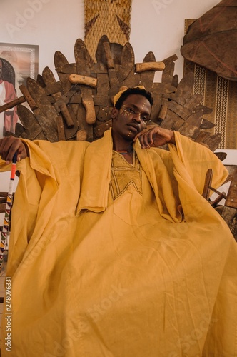 man in yellow rob e sits on brown throne