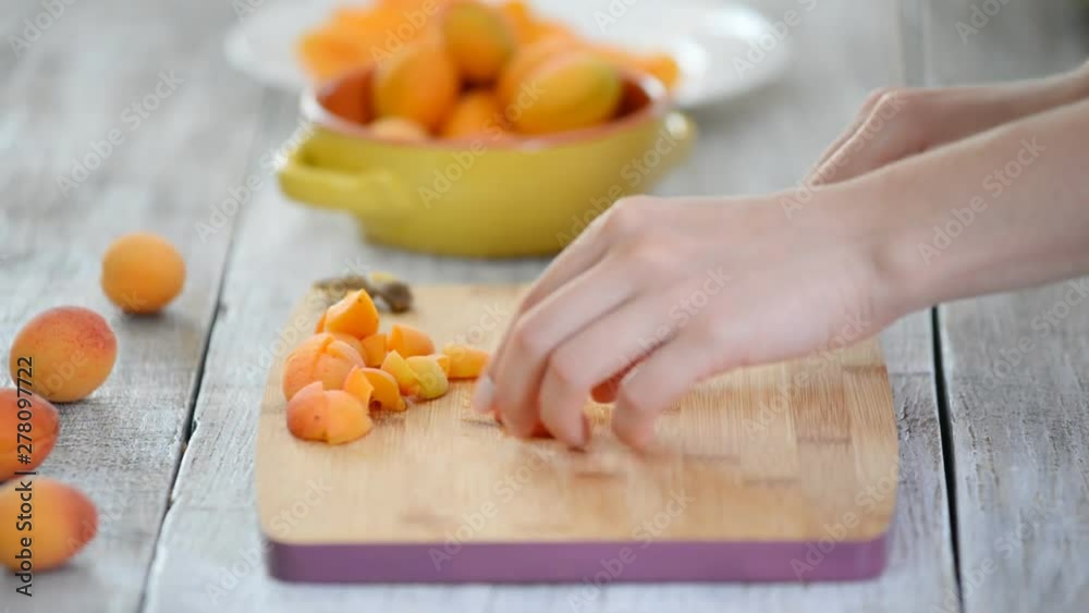 Close-up of female hands cutting apricots with a knife on a cutting board. Cooking Vegetarian Food. Close-up of female hands cutting apricots with a knife on a cutting board. Cooking Vegetarian Food.