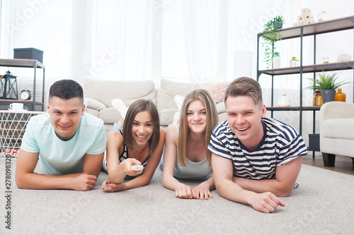 Group of young people watching tv. Active youth at home cheering on the team. Cheerful friends indoors having fun together.