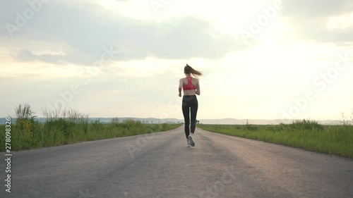 Shot back road runner woman running field sunset exercising outdoors fitness tracker wearable training marathon workout morning fitness adventure energy nature girl jogging healthy fit slow motion