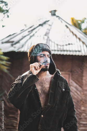 smoking man wearing black jacket near house photo