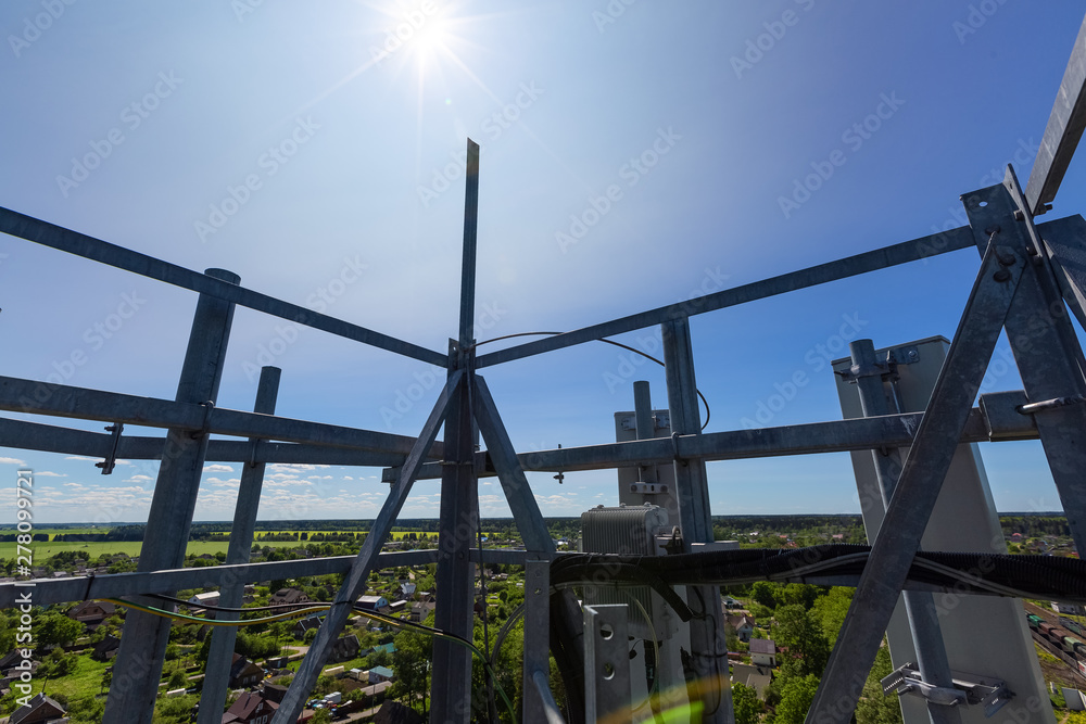 Telecommunication tower or mast with microwave, radio panel antennas, outdoor remote radio units, power cables, coaxial cables, optic fibers are on the top mast that located in town 