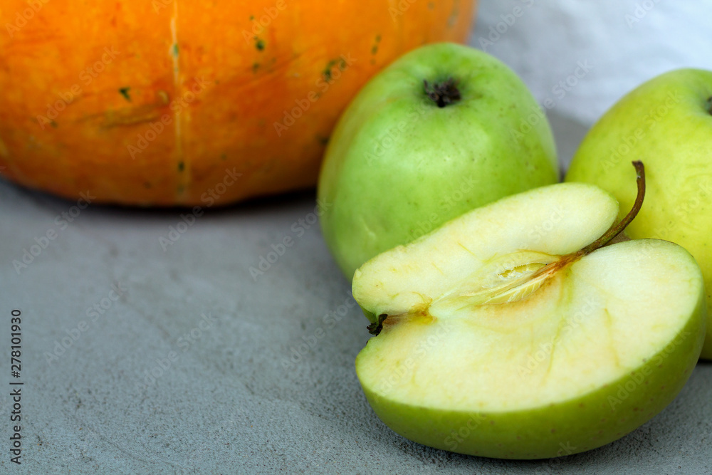 green apples on grey table. green apple and sweet pumpkin on grey background green apples on grey table. green apple and sweet pumpkin on grey background