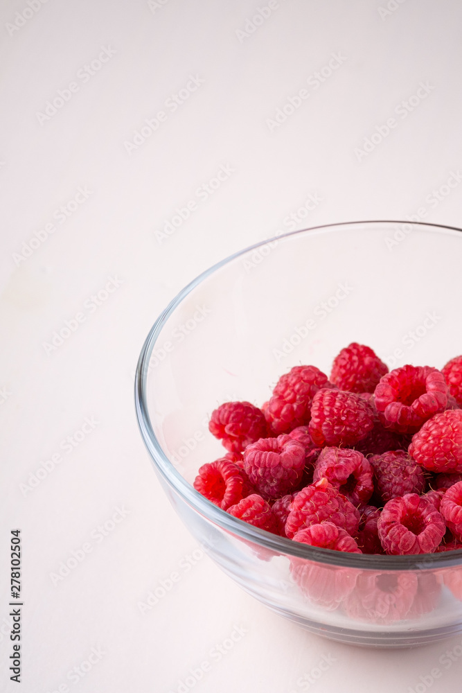 Raspberry red berries in transparent glass bowl plate tasty sweet bright on white background copy space macro Raspberry red berries in transparent glass bowl plate tasty sweet bright on white background copy space macro