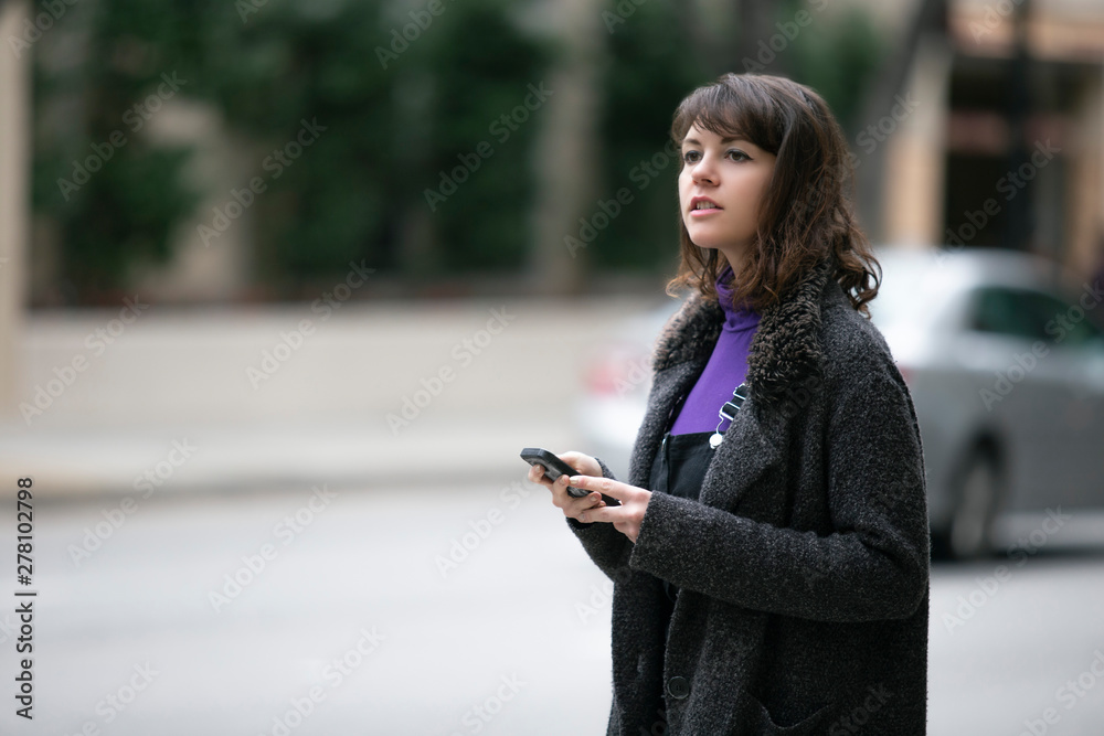Young female using mobile phone app and waiting for a rideshare or