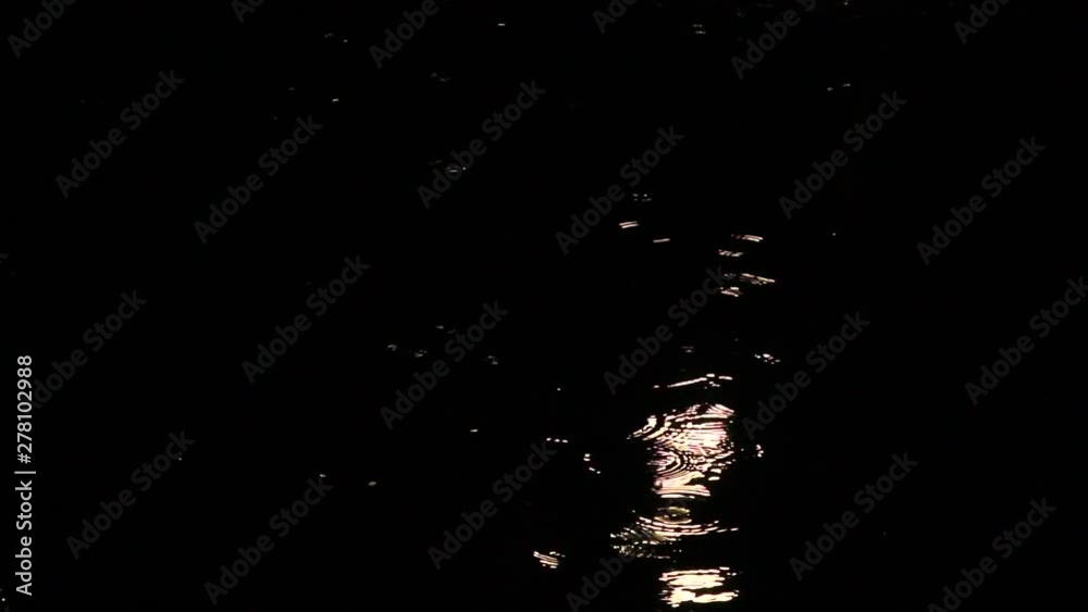rain at night drips through the puddles. circles on the water from the drops, illuminated by the light from the street lamp. autumn weather.