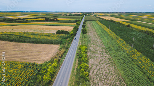 Asphalt road through fields and villages, aerial view