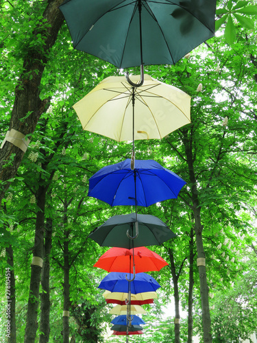 Umbrellas bright multi-colored hanging between the trees in the park