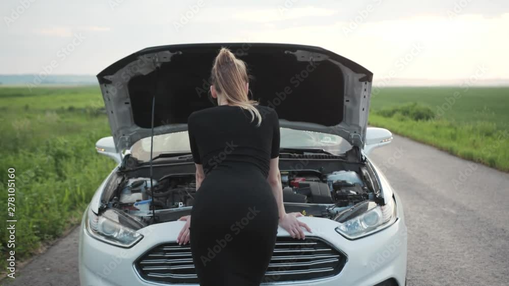 Close up shot back young woman looking at the engine of breakdown car at the field rural alone automobile girl help hood lost road trouble upset field repair side transportation travel slow motion