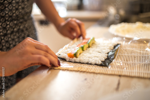 A Woman preparing homemade sushi and rolls. Forming sushi. The steps for creating sushi. View of process of preparing rolling sushi.