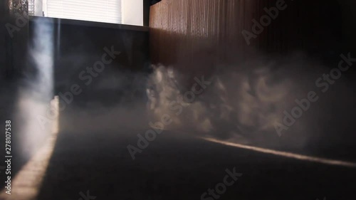 the smoke in the room spreads across the floor through the strip of sunlight. the beginning of the fire in the apartment in the middle of the day.