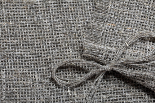 Coarse linen fabric. On it lies a bow of linen thread.