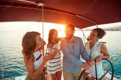friends on vacation travel on boat together and have fun at sunset.