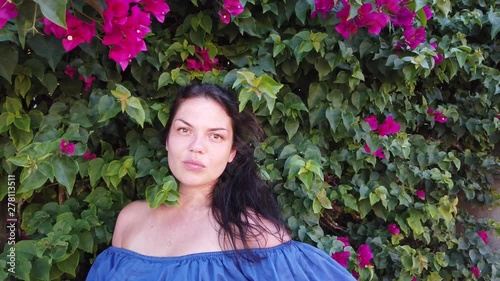 Young attractive brunette woman walks on the background of red spring flowers in park. Girl with red flowers in her hands.
