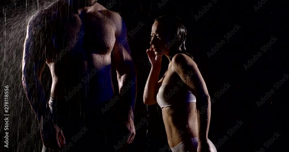 sexy woman in lingerie is dancing near naked muscular torso of man under rain in darkness sexy woman in lingerie is dancing near naked muscular torso of man under rain in darkness