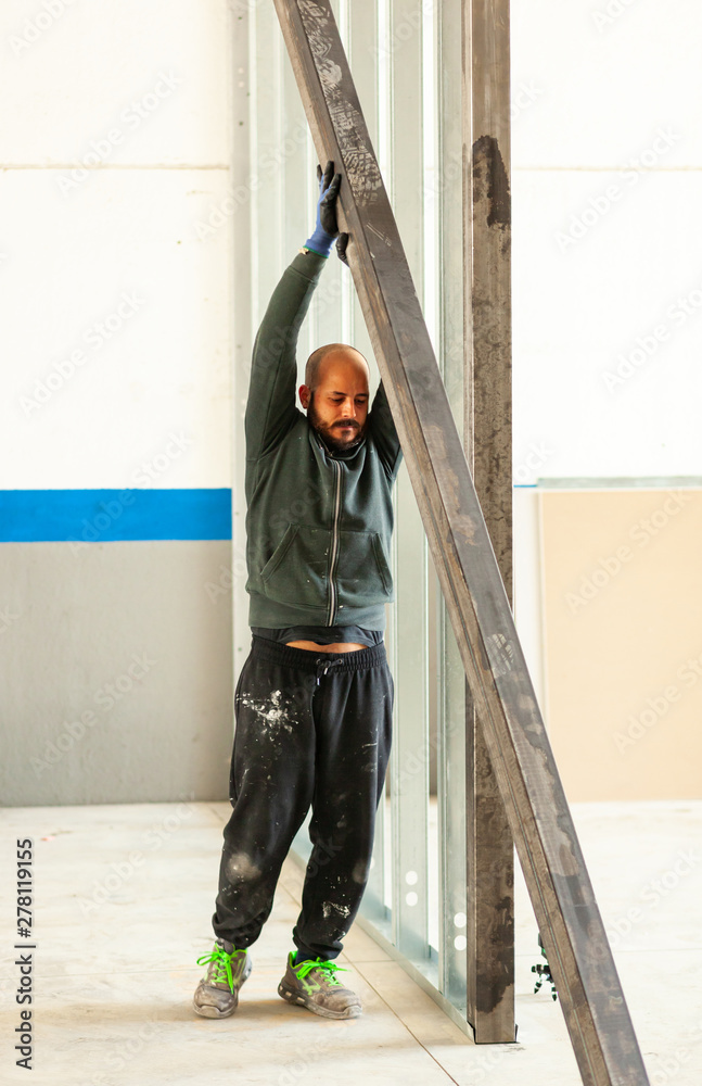 Worker builds a plasterboard wall.