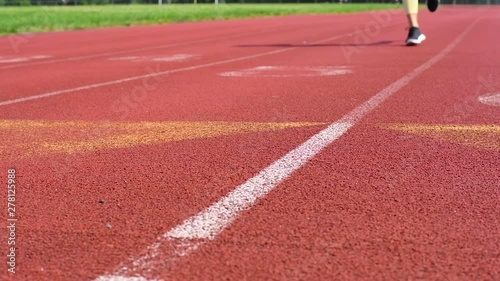 Close-up feet of woman running on track at outdoor