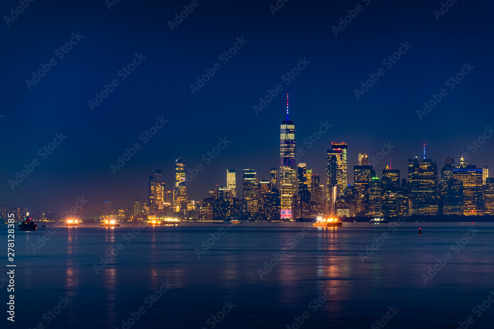 New York City Manhattan skyline illuminated with lights at dusk after sunset, view from New York Bay and Staten Island