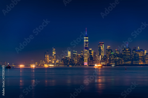 New York City Manhattan skyline illuminated with lights at dusk after sunset, view from New York Bay and Staten Island