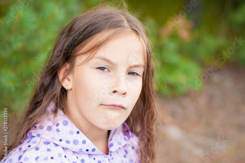 Sad little girl is looking with serious face at camera