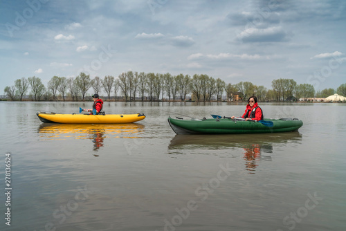 Kayak fishing at lake. Two fisherwomen on inflatable boats with fishing tackle. © FedBul