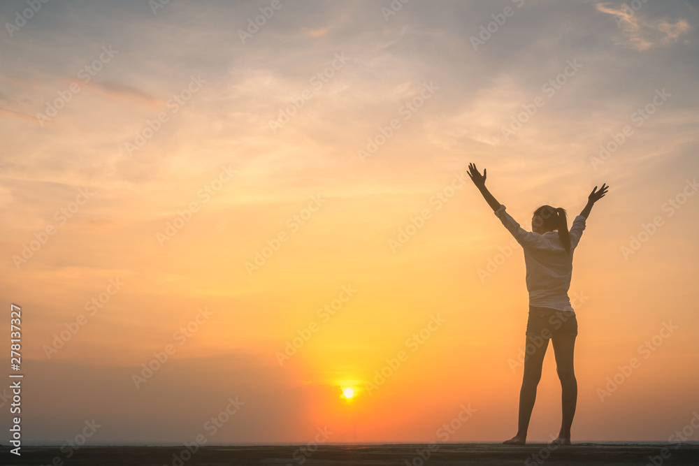 Silhouette of free woman enjoying freedom feeling happy at sunset. Serene relaxing woman in pure happiness