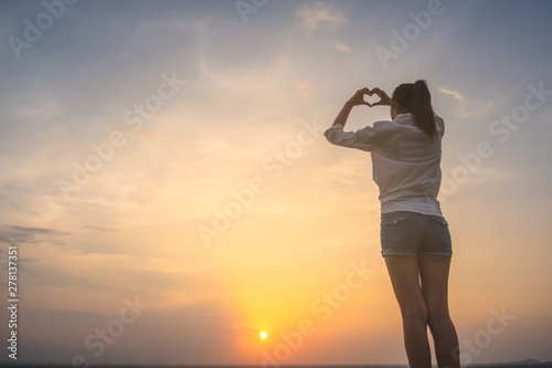 Girl holding a heart - shape symbol with her hands   fingers.