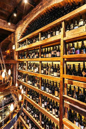 Wine cellar on the wall in Italian restaurant decorated with brick in warm light that created cozy atmosphere.