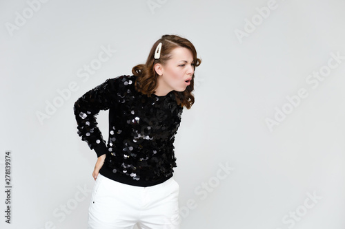 Portrait below the belt on a white background pretty young brunette woman in a black sweater and white trousers with glitters. Standing in different poses, talking, showing emotions.