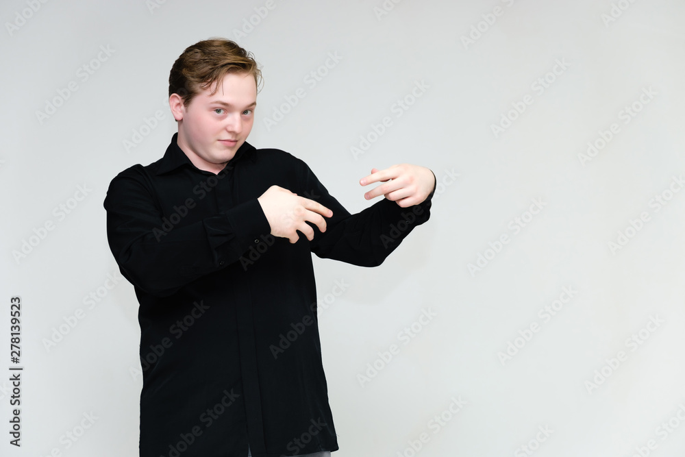 Portrait to the waist on a white background of a handsome young man in a black shirt. stands directly in front of the camera in different poses, talking, showing emotions, showing hands. Portrait to the waist on a white background of a handsome young man in a black shirt. stands directly in front of the camera in different poses, talking, showing emotions, showing hands.