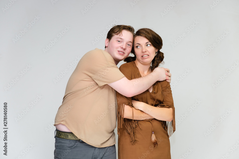 Portrait below the belt on a white background pretty young brunette woman in a brown dress and a young man in a brown shirt. Standing in different poses, talking, showing emotions. Portrait below the belt on a white background pretty young brunette woman in a brown dress and a young man in a brown shirt. Standing in different poses, talking, showing emotions.