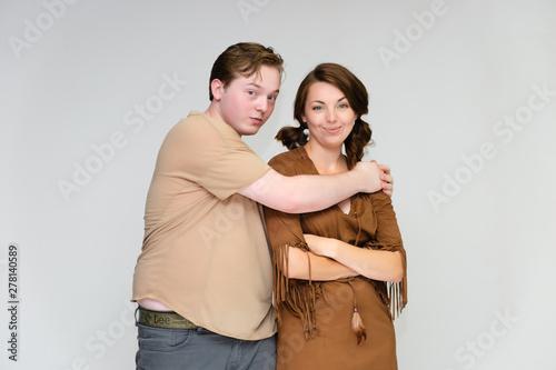Portrait below the belt on a white background pretty young brunette woman in a brown dress and a young man in a brown shirt. Standing in different poses, talking, showing emotions.
