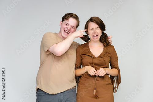 Portrait below the belt on a white background pretty young brunette woman in a brown dress and a young man in a brown shirt. Standing in different poses, talking, showing emotions.