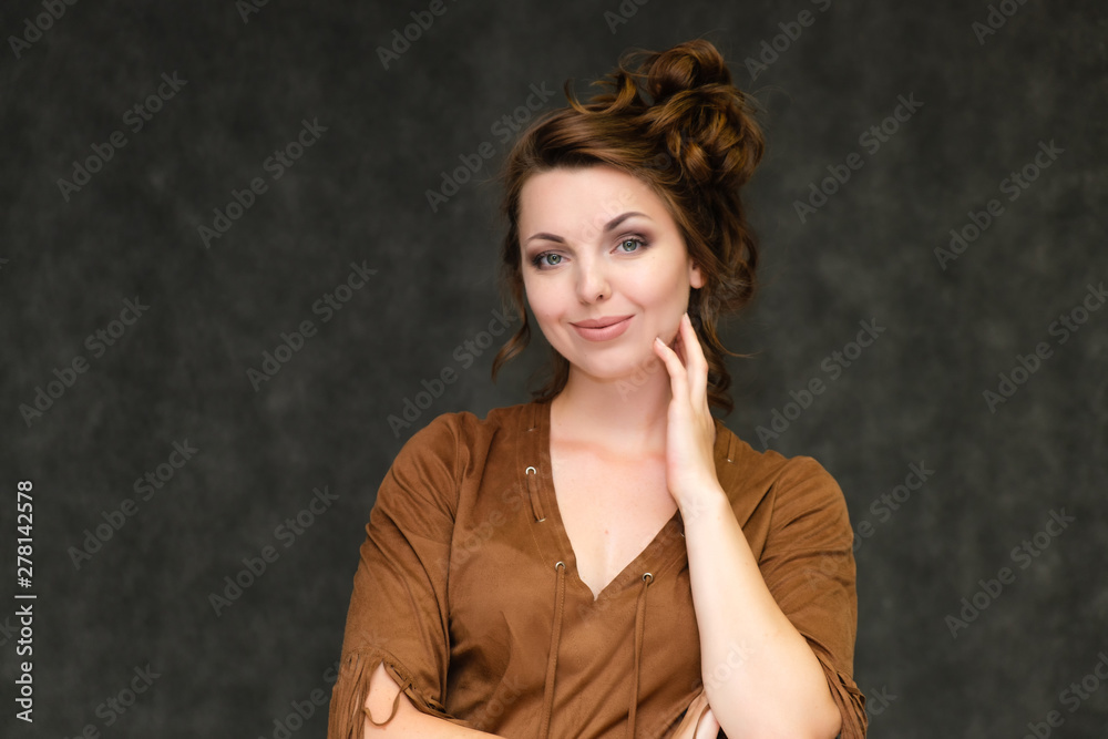 Portrait below breast over gray background of pretty young brunette woman in brown dress with beautiful hair. Standing in different poses, talking, showing with hands, demonstrating emotions. Portrait below breast over gray background of pretty young brunette woman in brown dress with beautiful hair. Standing in different poses, talking, showing with hands, demonstrating emotions.