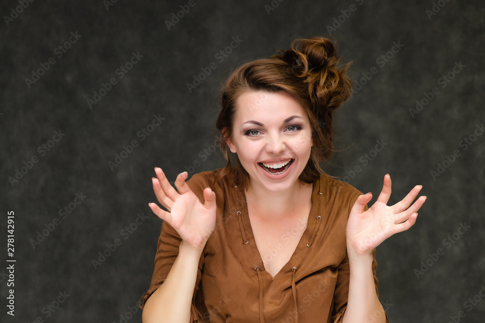 Portrait below breast over gray background of pretty young brunette woman in brown dress with beautiful hair. Standing in different poses, talking, showing with hands, demonstrating emotions. Portrait below breast over gray background of pretty young brunette woman in brown dress with beautiful hair. Standing in different poses, talking, showing with hands, demonstrating emotions.