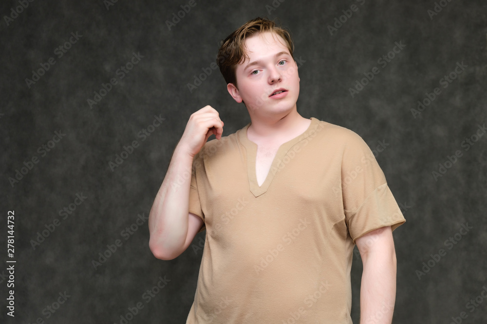 Portrait to the waist on a gray background of a handsome young man in a brown T-shirt. stands directly in front of the camera in various poses, talking, demonstrating emotions.