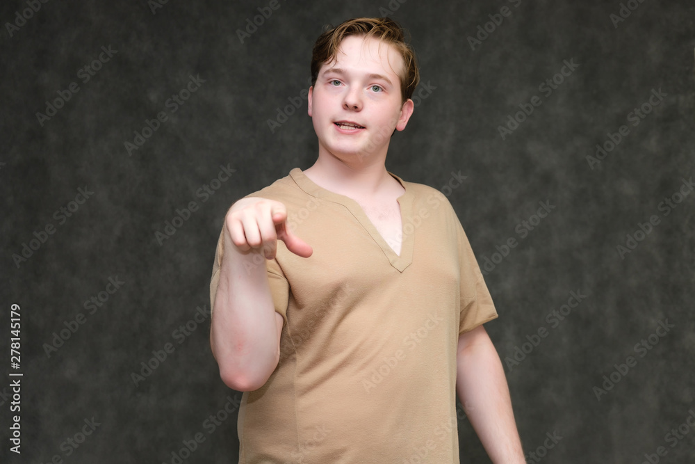 Portrait to the waist on a gray background of a handsome young man in a brown T-shirt. stands directly in front of the camera in various poses, talking, demonstrating emotions. Portrait to the waist on a gray background of a handsome young man in a brown T-shirt. stands directly in front of the camera in various poses, talking, demonstrating emotions.