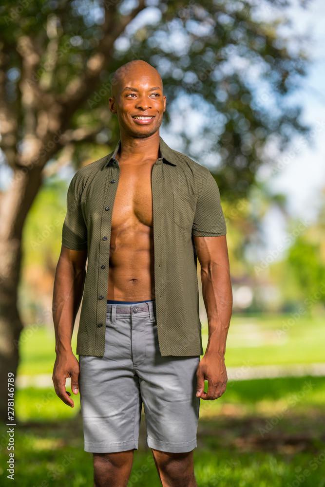 Sexy male model posing in the park with shirt unbuttoned showing muscular chest Sexy male model posing in the park with shirt unbuttoned showing muscular chest