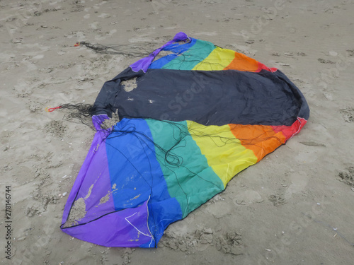 kite in rainbowcolors with black threads laying on the beach of Velsen Netherlands photo