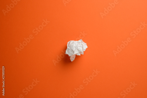 Papel arrugado sobre fondo liso de color naranja