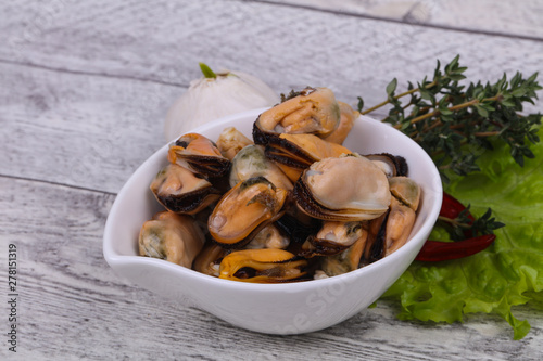 Pickled mussels in the bowl served pepper, garlic and salad